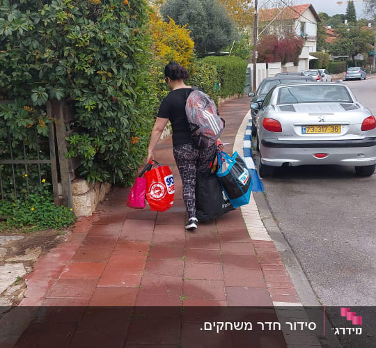 אישה נושאת שקיות קניות צבעוניות על מדרכה
